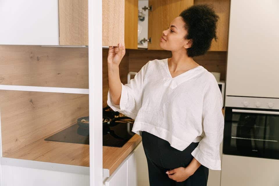 Femme qui regarde dans les placards de sa cuisine